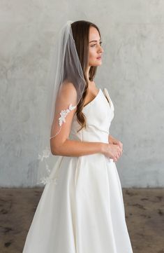 a woman in a wedding dress with a veil on her head looking off to the side