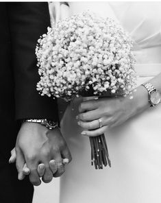 a bride and groom holding hands with flowers in their lapel bracelets on their wedding day