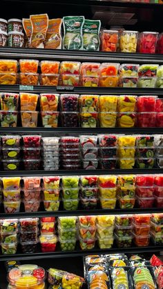 a display case filled with lots of different types of fruits and veggies in plastic containers