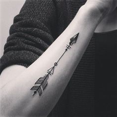 a woman's arm with an arrow tattoo on it