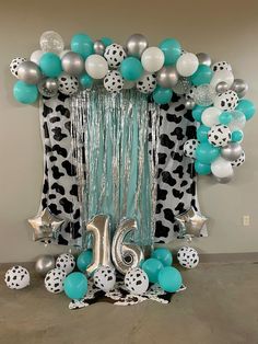 the balloon arch is decorated with black and white balloons, silver confetti, and teal streamers