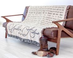 a pair of cowboy boots sitting on top of a wooden chair next to a blanket