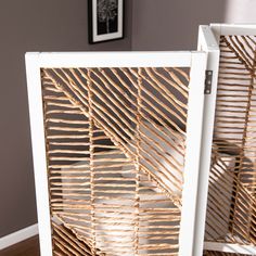 two pieces of rattan are sitting on the floor in front of a wall with pictures