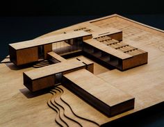 a wooden model of a house on top of a table with blueprints and wood