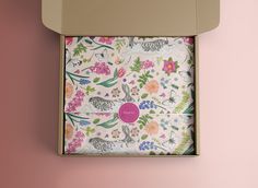 an open box with a pink and green floral print on the inside, sitting on a pink wall