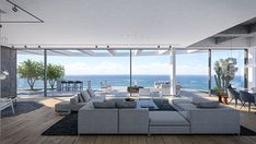 a modern living room with large windows overlooking the ocean is furnished in white and grey