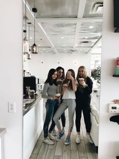 four women taking a selfie in the mirror at a coffee shop with their cell phones