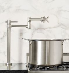 a stainless steel pot sitting on top of a stove next to a faucet