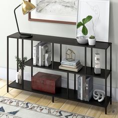 a black shelf with books and other items on it next to a wall mounted painting