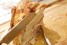 a chicken being cut with a knife on a cutting board