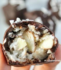 a person holding up a piece of chocolate covered in white and brown toppings on top of it