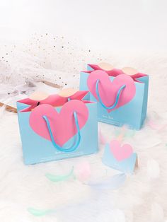 two paper bags with hearts on them sitting on a bed