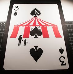 a playing card with the silhouettes of two people and a circus tent