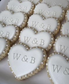 heart shaped cookies with white frosting and monogrammings on them are arranged in the shape of hearts