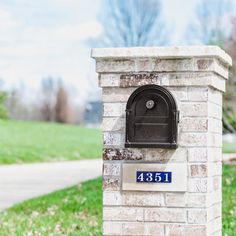 a brick mailbox with a blue and white plate on the front is sitting in grass