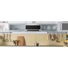 a kitchen with yellow and white walls, cabinets and microwaves on the wall next to pots and pans