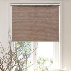 a living room with a couch, table and window blinds in shades of brown color