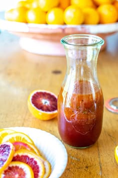 a bottle of blood orange juice sitting on top of a wooden table next to slices of grapefruit