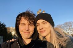 a young man and woman are posing for a photo in front of the city skyline