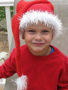 a young boy wearing a red hat with white pompoms