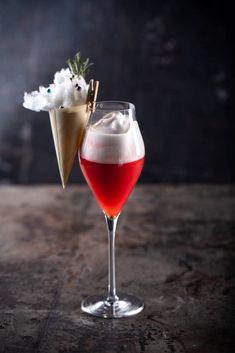 two glasses filled with liquid on top of a wooden table next to cotton floss