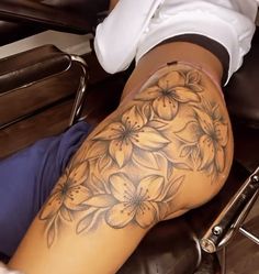 a woman's leg with flowers on it and a chair in front of her