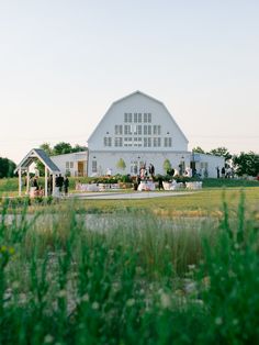 a large white barn sitting on top of a lush green field