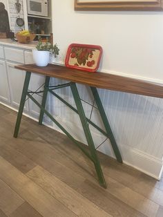 a wooden table sitting on top of a hard wood floor next to a white wall