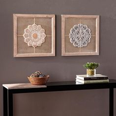 two wall hangings on the side of a table with a potted succulent