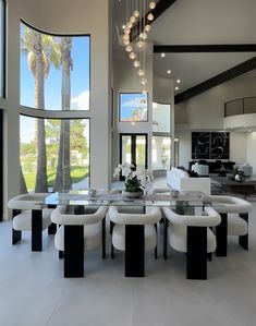 a dining room table with white chairs around it and large windows overlooking the golf course