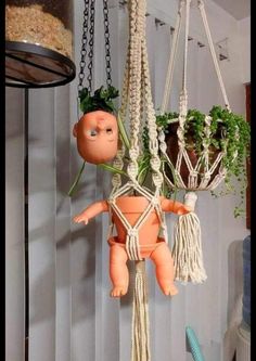 an orange doll hanging from a rope with plants in it