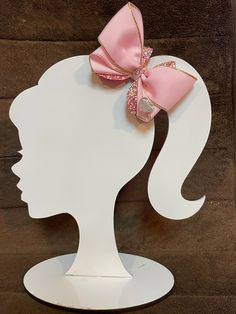 a white silhouette with a pink bow on it's head, against a brown background