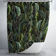 a shower curtain with green leaves on black and white background, hanging in a bathroom