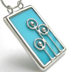 a necklace with scissors on it is shown in blue and silver colors, sitting on a white surface