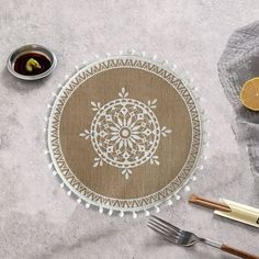 the table is set with silverware, lemons and an embroidered doily on it