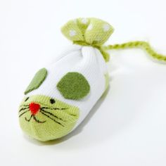 a cat shaped keychain is shown on a white surface with green dots around it