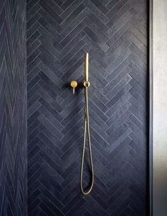 a shower head and hand held shower faucet in a bathroom with black herringbone tile