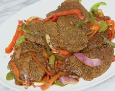 a white plate topped with meat and veggies on top of a marble table