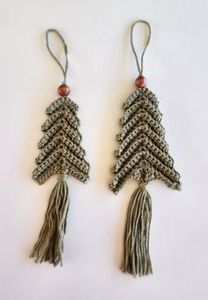 two tasseled christmas trees hanging from strings on a white surface with wood beads