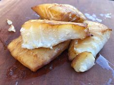 some food that is sitting on top of a wooden cutting board and has been cut into pieces