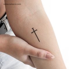 a woman's arm with a cross tattoo on the left side of her arm