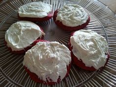 four red velvet cupcakes with white frosting on a glass plate, ready to be eaten