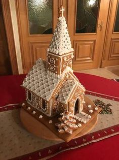 a gingerbread house is on the floor in front of a wooden door and red carpet