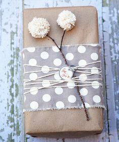 a present wrapped in brown paper with white polka dots and pom - poms