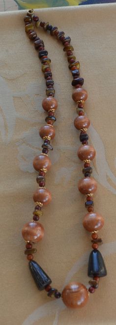 "Featuring this very attractiveshades of brown beaded necklace that is a mix of wooden, stone and horn beads. The wooden beads have gold tone filigree cap accents. The necklace measures 26\" in length and has a spring ring clasp. The necklace is in very good vintage condition." Bohemian Brown Hand-strung Beaded Necklaces, Bohemian Brown Hand-strung Beaded Necklace, Adjustable Brown Wooden Necklaces, Elegant Brown Hand-strung Beaded Necklaces, Brown Spiritual Jewelry With Large Beads, Vintage Brown Wooden Bead Necklaces, Brown Wooden Necklace With Large Beads, Wooden Brown Beaded Necklace Gift, Brown Wooden Beaded Necklace Gift