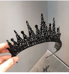 a woman holding up a black tiara