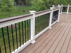 a wooden deck with white railings and black rails