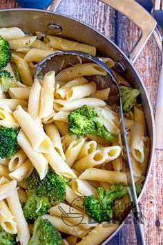 a pot filled with pasta and broccoli on top of a wooden table