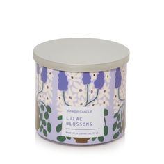 a candle that is in a tin with flowers on it and the words lilac blossoms written