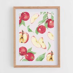 an apple print hangs on the wall next to a wooden framed frame with green leaves and red apples